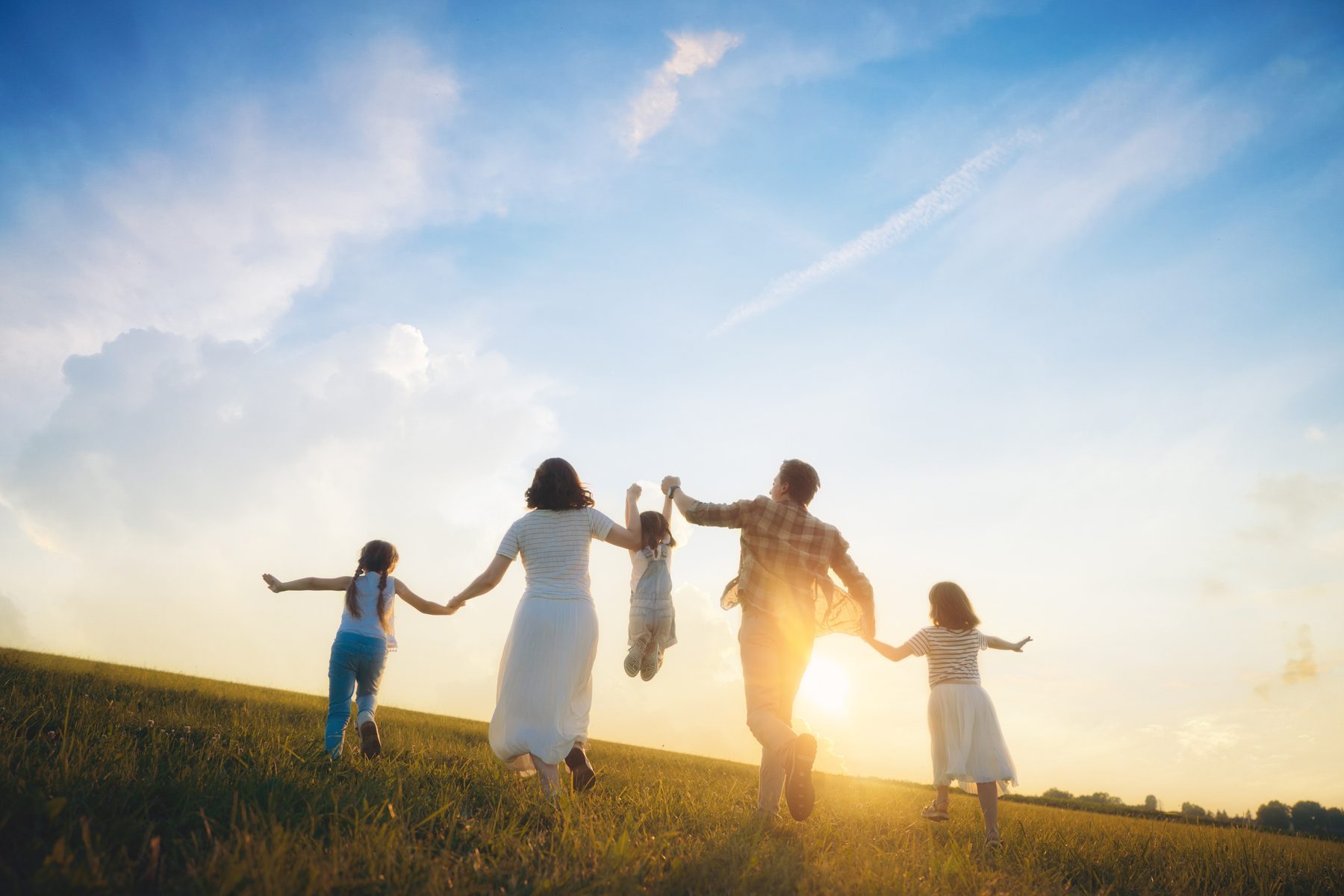 A family walking together across a field at sunset