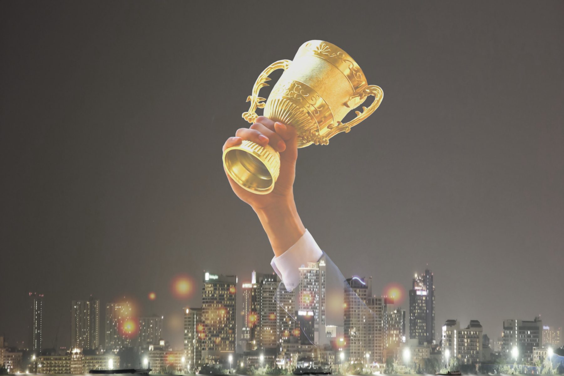 A raised golden trophy above a city skyline at night